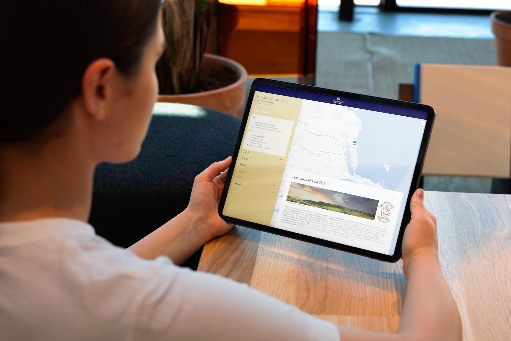 Person holding a tablet displaying an interactive travel map by TraveledMap created in collaboration with SignatureGolf