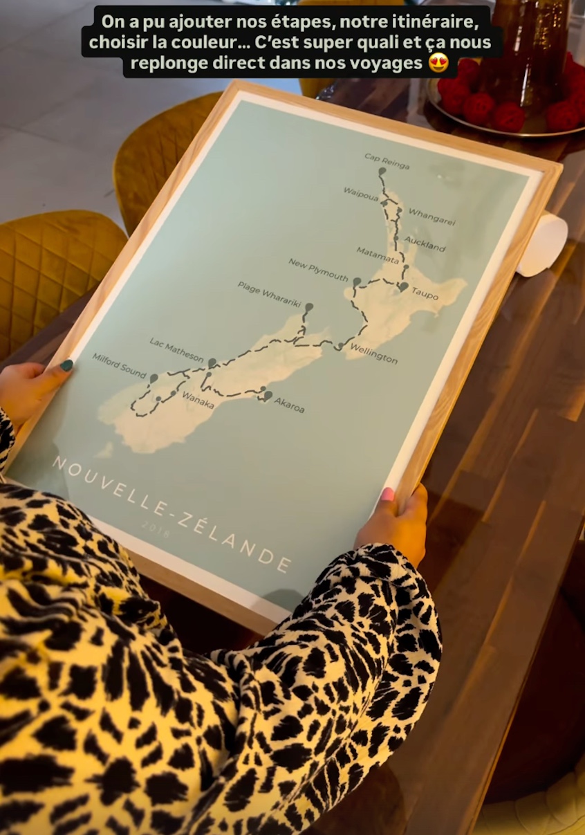 Person holding a framed pastel blue travel itinerary poster of New Zealand